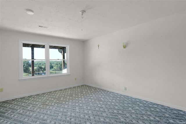 carpeted empty room with a textured ceiling and baseboards