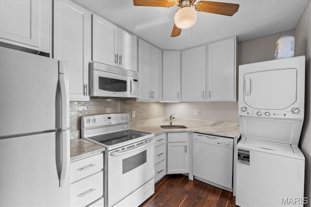 1436 Peacock Ln, Saint Louis, MO 63144 - kitchen with white appliances, stacked washer and clothes dryer, a sink, dark wood-style flooring, and a textured ceiling