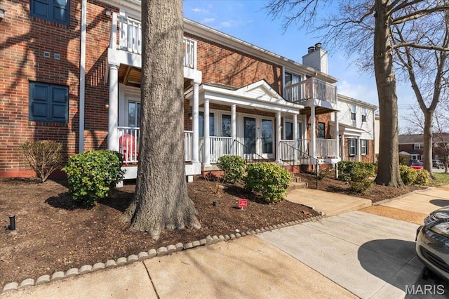 1436 Peacock Ln, Saint Louis, MO 63144 - view of front of house with a porch, a balcony, brick siding, a chimney, and french doors