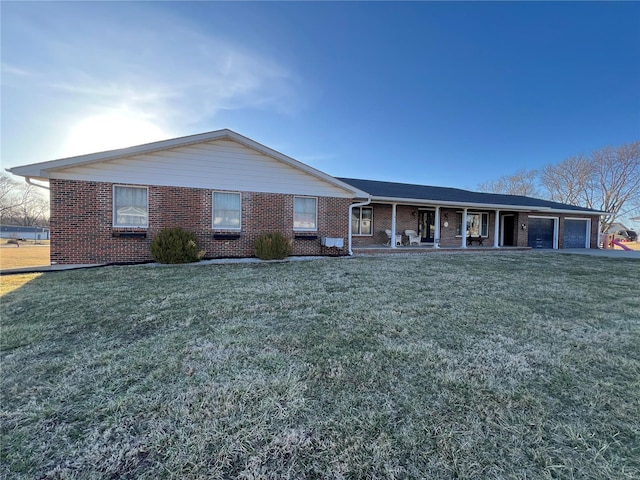 single story home with covered porch, brick siding, a front lawn, and a garage