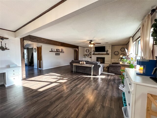 living room featuring a textured ceiling, dark wood-style floors, a fireplace, ceiling fan, and baseboards