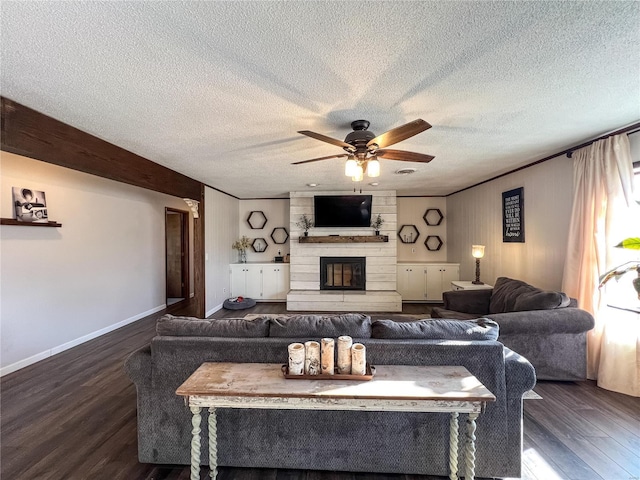 living room featuring wood finished floors, a ceiling fan, baseboards, a textured ceiling, and a large fireplace