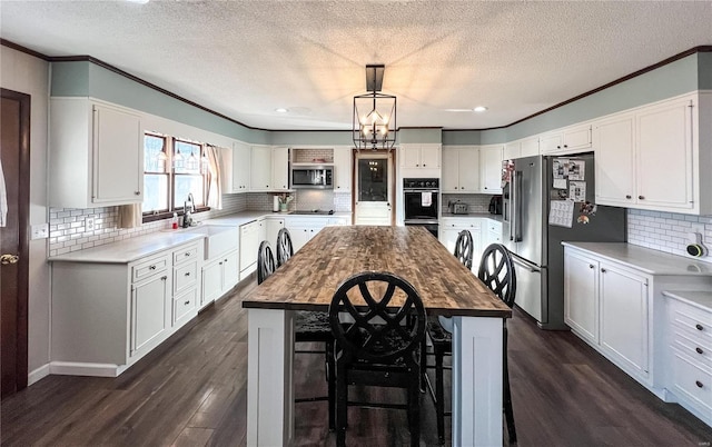 kitchen featuring wooden counters, black appliances, independent washer and dryer, a sink, and crown molding
