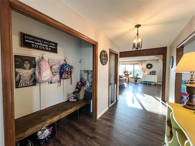mudroom featuring dark wood-style floors, a textured ceiling, baseboards, and a chandelier