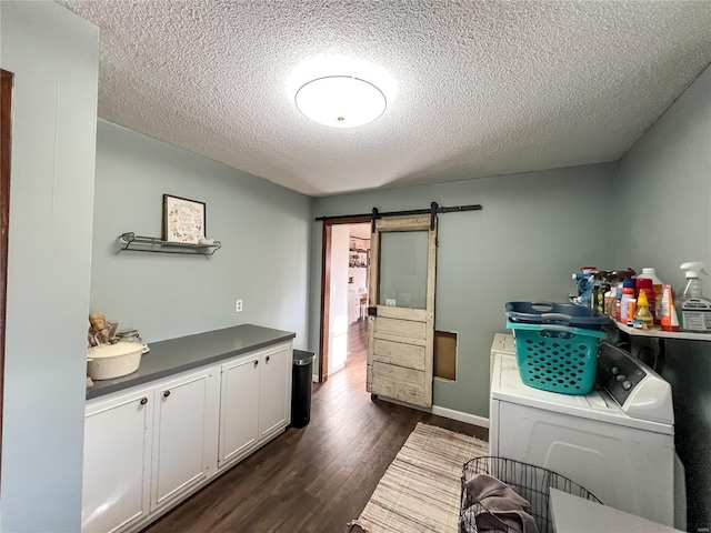 laundry area featuring cabinet space, washer and dryer, a textured ceiling, dark wood-type flooring, and a barn door