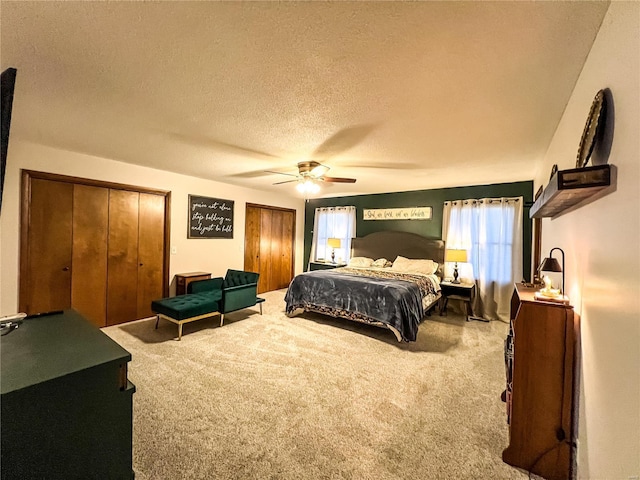 bedroom with carpet, a textured ceiling, multiple closets, and ceiling fan
