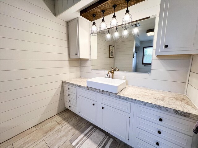 bathroom with vanity, wood finished floors, a shower, and wooden walls