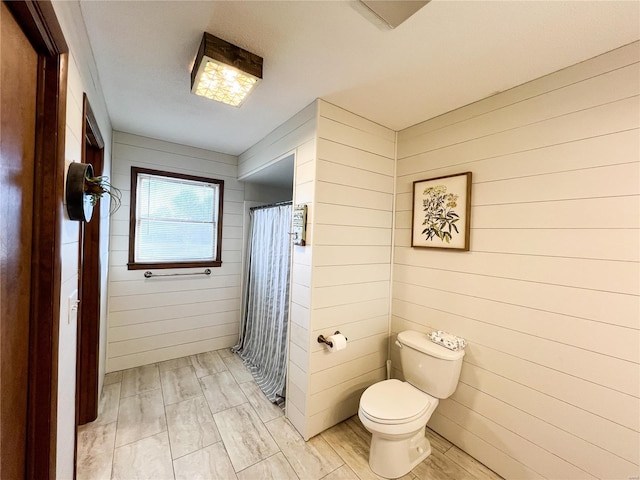 full bathroom featuring wooden walls, toilet, curtained shower, and wood finished floors