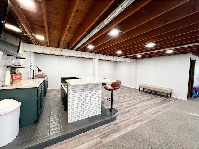 finished below grade area featuring a dry bar, baseboards, and dark carpet