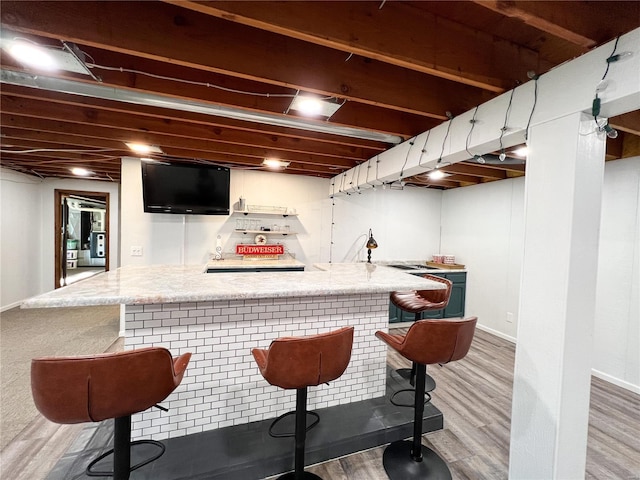 indoor wet bar featuring light wood finished floors and baseboards