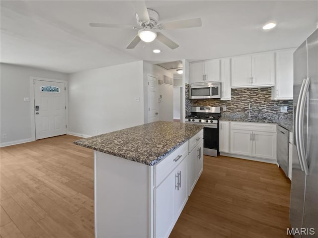 1248 Green Knoll Dr, Fenton, MO 63026 - kitchen with stainless steel appliances, a ceiling fan, white cabinetry, light wood finished floors, and decorative backsplash