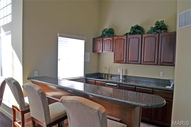13101 Mill Crossing Ct Unit 200, Saint Louis, MO 63141 - kitchen featuring a sink, a kitchen bar, dishwasher, a peninsula, and dark stone countertops