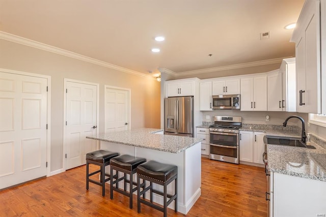 24345 State Route Ww Unit 40/41, Saint Genevieve, MO 63670 - kitchen with stainless steel appliances, a sink, ornamental molding, wood finished floors, and a kitchen bar