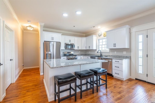 24345 State Route Ww Unit 40/41, Saint Genevieve, MO 63670 - kitchen with appliances with stainless steel finishes, a center island, a breakfast bar area, white cabinets, and ornamental molding