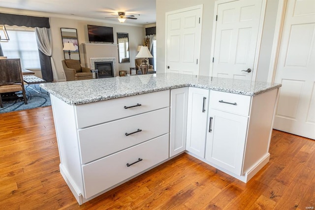 24345 State Route Ww Unit 40/41, Saint Genevieve, MO 63670 - kitchen with ornamental molding, ceiling fan, light wood-style flooring, a glass covered fireplace, and white cabinets