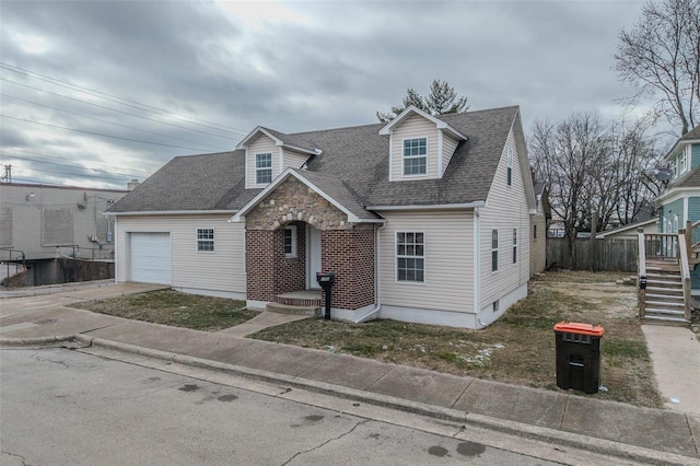 view of front of home with an attached garage, driveway, roof with shingles, fence, and stone siding