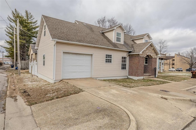 view of side of property with driveway, an attached garage, and a shingled roof