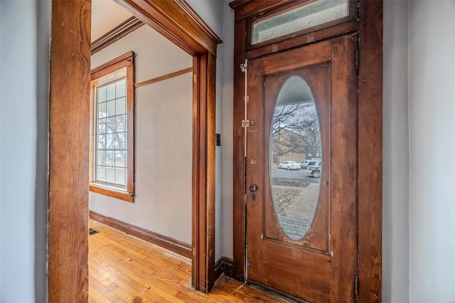 entrance foyer with healthy amount of natural light, wood finished floors, baseboards, and crown molding