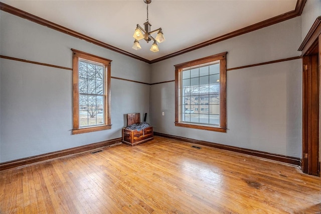 spare room featuring wood-type flooring, baseboards, ornamental molding, and a chandelier