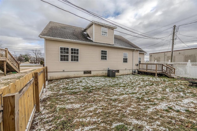 back of property with a fenced backyard, a wooden deck, cooling unit, and roof with shingles