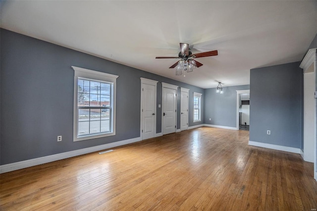 unfurnished living room with a ceiling fan, baseboards, and wood-type flooring