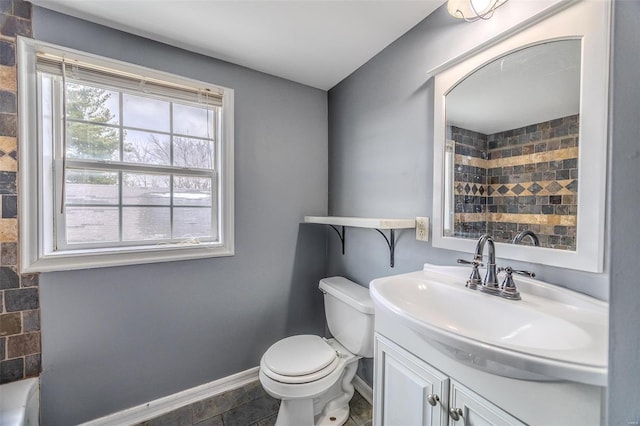bathroom featuring toilet, vanity, and baseboards