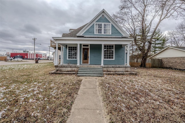 view of front of house with covered porch, fence, and a shingled roof