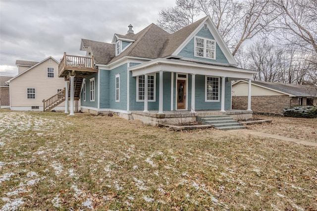 view of front of home featuring roof with shingles, stairway, covered porch, and a chimney
