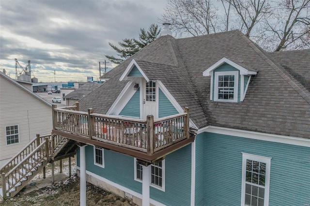 rear view of property with a wooden deck, a shingled roof, and stairs