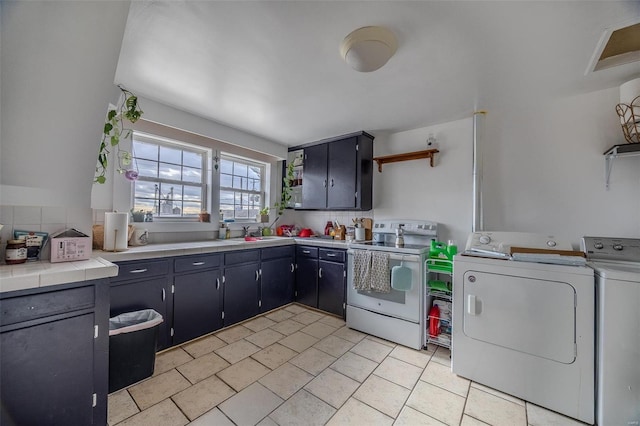 kitchen with white electric range oven, open shelves, washing machine and clothes dryer, a sink, and tasteful backsplash