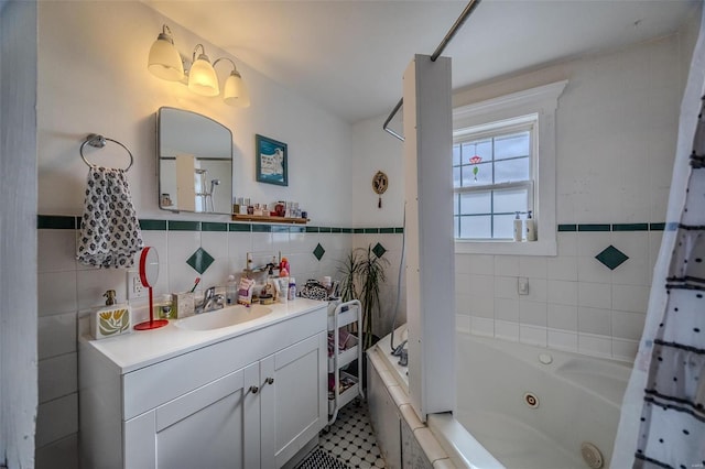 full bathroom with tile walls, vanity, a combined bath / shower with jetted tub, and wainscoting