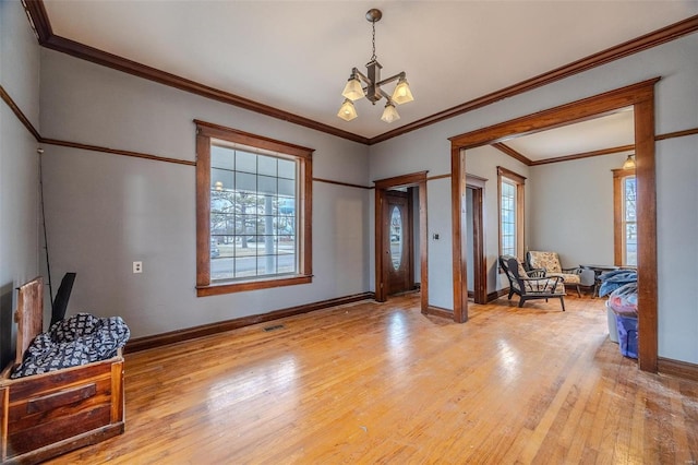 foyer with healthy amount of natural light, light wood-style floors, baseboards, and crown molding