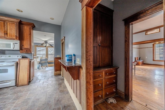 kitchen with white appliances, ceiling fan, brown cabinetry, and plenty of natural light