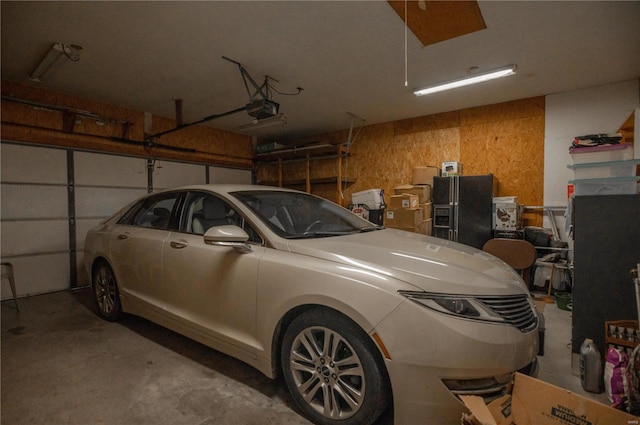 garage featuring a garage door opener and black refrigerator with ice dispenser