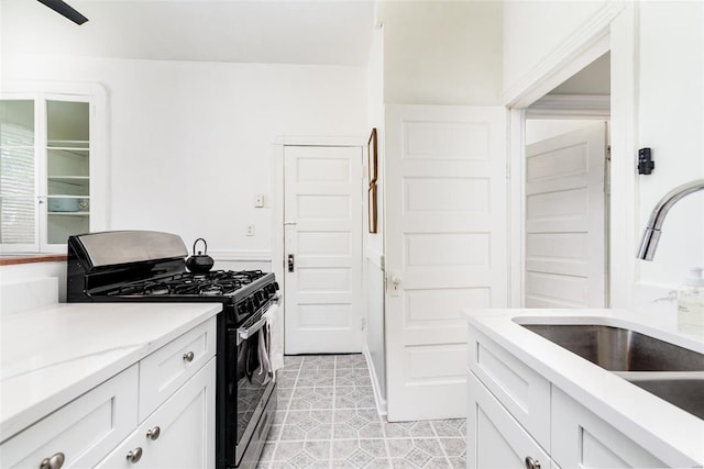 4271 Botanical Ave, Saint Louis, MO 63110 - kitchen with black gas range, a sink, white cabinetry, light stone counters, and light tile patterned floors