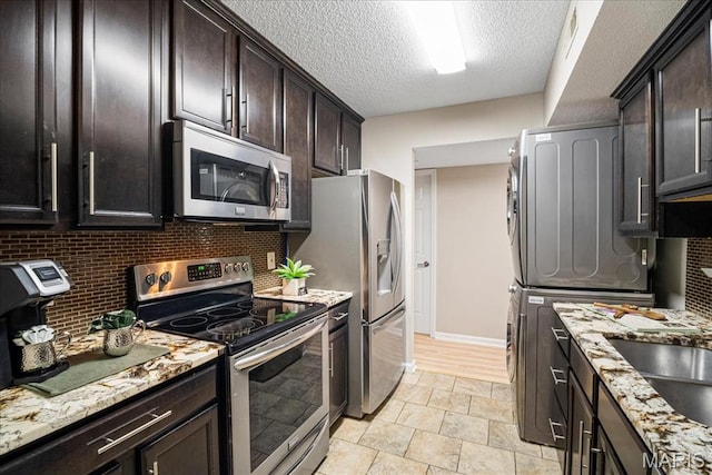 1528 Thrush Ter, Brentwood, MO 63144 - kitchen with stainless steel appliances, stacked washer / dryer, backsplash, dark brown cabinets, and light stone countertops