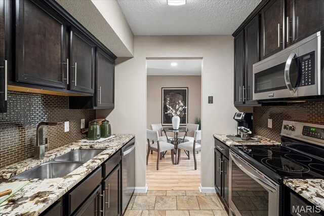1528 Thrush Ter, Brentwood, MO 63144 - kitchen featuring appliances with stainless steel finishes, a sink, light stone countertops, baseboards, and tasteful backsplash
