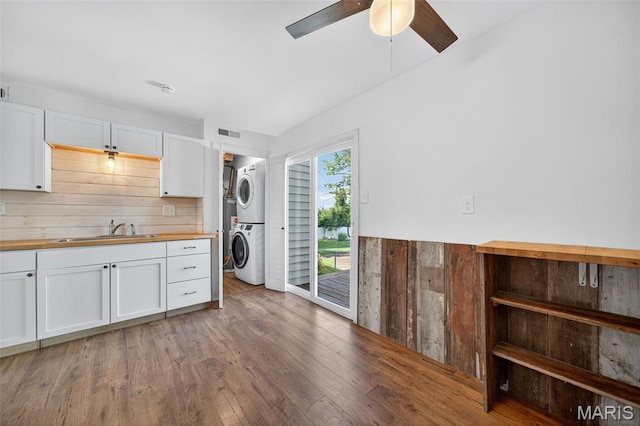 104 Wild Winds Dr, Ofallon, MO 63368 - laundry room featuring stacked washer / dryer, a ceiling fan, light wood-type flooring, and wood walls