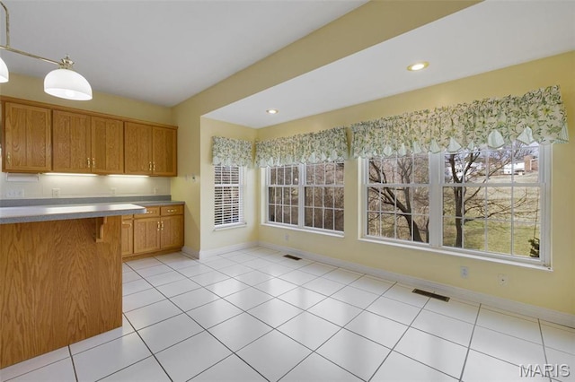 1736 Debra Ln, Arnold, MO 63010 - kitchen featuring brown cabinets, baseboards, decorative light fixtures, a breakfast bar area, and recessed lighting