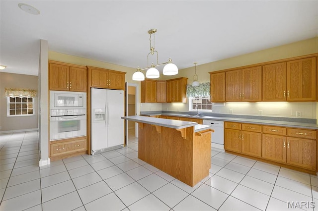 1736 Debra Ln, Arnold, MO 63010 - kitchen featuring white appliances, a kitchen island, light countertops, brown cabinets, and a kitchen bar