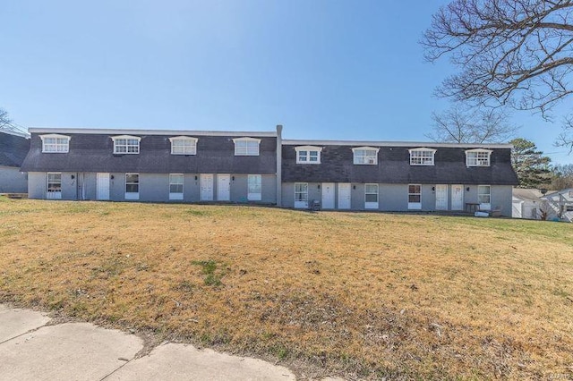 rear view of property with a lawn, a shingled roof, and mansard roof