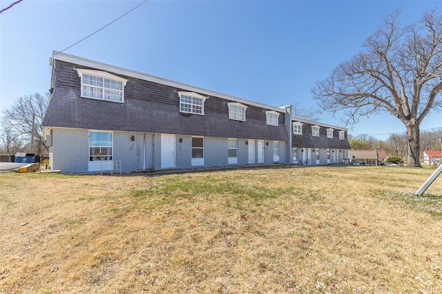 back of house with brick siding, a yard, and a shingled roof