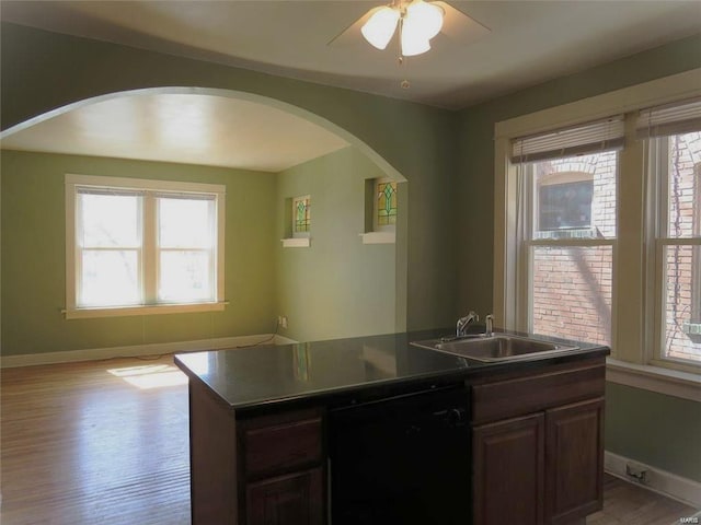 2039 Maury Ave, Saint Louis, MO 63110 - kitchen featuring black dishwasher, a sink, light wood-style flooring, baseboards, and arched walkways