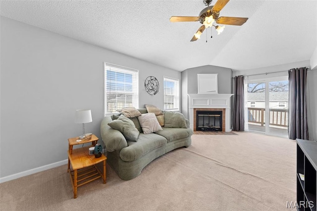 carpeted living room featuring ceiling fan, a tile fireplace, a textured ceiling, vaulted ceiling, and baseboards