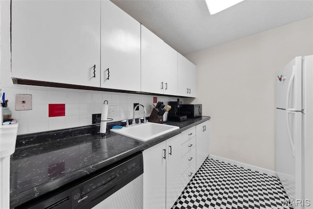 kitchen with freestanding refrigerator, stainless steel dishwasher, a sink, tile patterned floors, and white cabinets