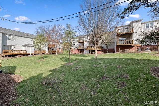 view of green lawn with a deck and a balcony