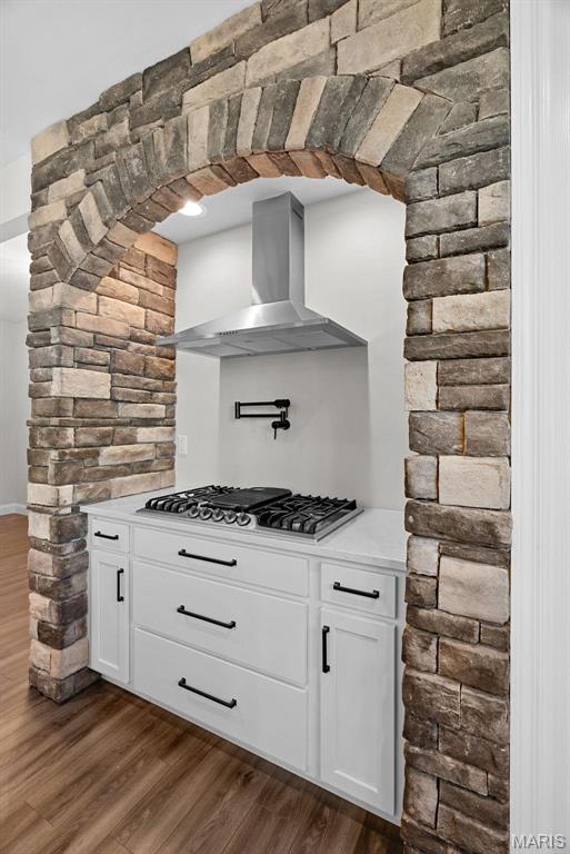 1 Canebrake Ct, Wentzville, MO 63385 - kitchen with wall chimney exhaust hood, stainless steel gas stovetop, dark wood-style floors, and white cabinets