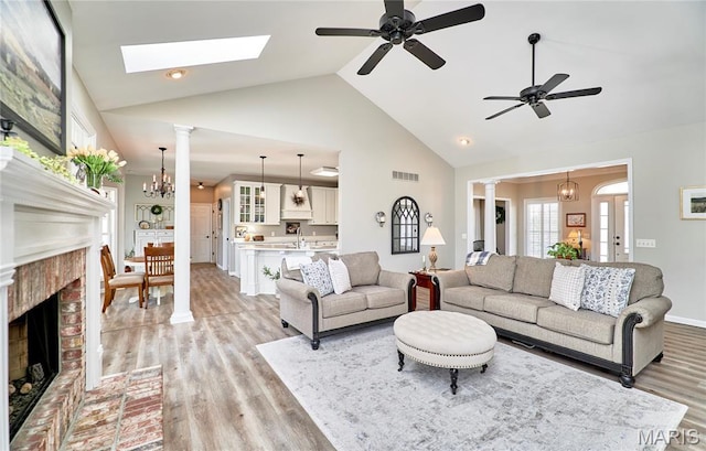 269 Bennington Dr, Troy, MO 63379 - living area with high vaulted ceiling, light wood-style floors, ceiling fan, ornate columns, and a brick fireplace