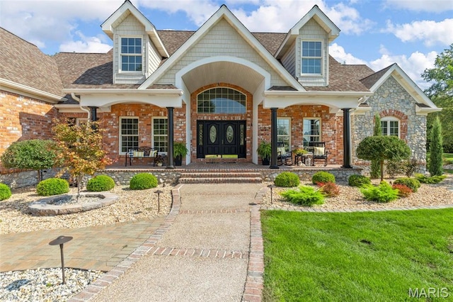 261 US Dr, Wentzville, MO 63385 - doorway to property featuring covered porch, roof with shingles, stone siding, and a yard