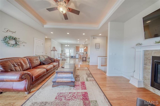 17205 Elk Prairie Dr, Rolla, MO 65401 - living room featuring a raised ceiling, a tiled fireplace, a ceiling fan, light wood-style flooring, and recessed lighting